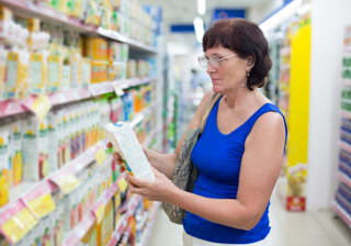 A woman reading packaged food labels in a supermarket 