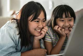 Two teens looking at a laptop screen smiling 