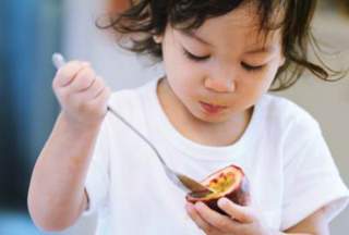 Toddler eating passionfruit with a spoon