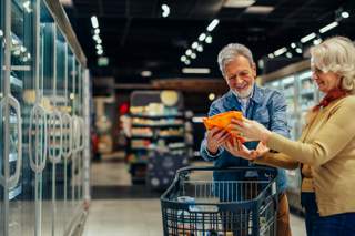 older couple looking at packet of food in supermarket