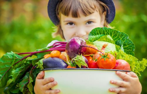 child holding veggies in a bowl