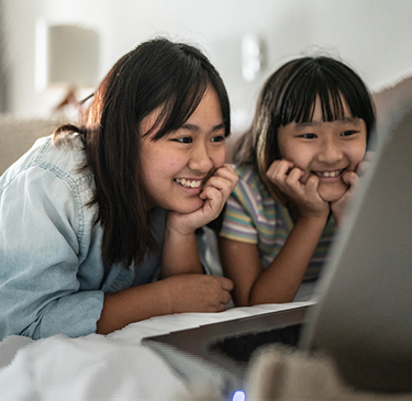 two girls smiling at computer